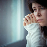Surullisen näköinen nuori istuu mietteissään ikkunan edessä. 